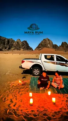 two people sitting next to a car on a beach with candles at MAYA RUM LUXURY CAMP & Jeep Tours in Disah