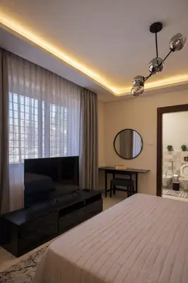 a bedroom with a bed and a television and a desk at Der Ghbar 3BR - 2 Terraces, Scenic Views & BBQ in Amman