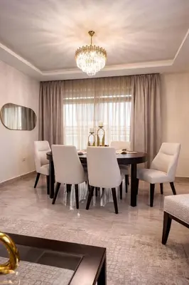 a dining room with a table and chairs and a chandelier at Der Ghbar 3BR - 2 Terraces, Scenic Views & BBQ in Amman