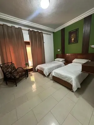 two beds in a room with green walls at Al Majd Hotel المجد للشقق الفندقية in Amman