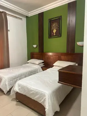three beds in a room with green walls at Al Majd Hotel المجد للشقق الفندقية in Amman