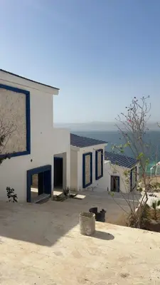 a white house with the ocean in the background at Santorini Resort & Spa in Sowayma
