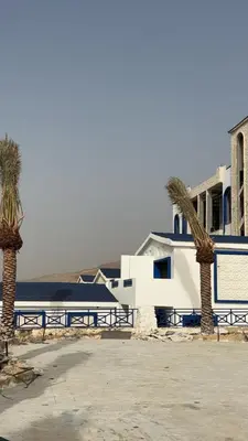 two palm trees in front of a building at Santorini Resort & Spa in Sowayma