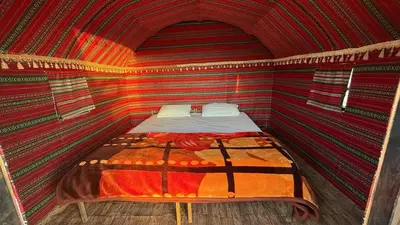 a bed in a room with a red and orange striped wall at Wadi Rum Desert Night Camp in Wadi Rum