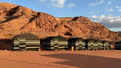 a row of domes in the desert near a mountain at Wadi Rum Desert Night Camp in Wadi Rum