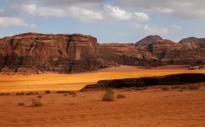 a desert scene with mountains and a dirt field at Wadi Rum Desert Night Camp in Wadi Rum