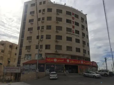 a large building with cars parked in front of it at Al Tawheed Hotel Apartments in Amman
