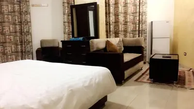 a bedroom with a bed and a couch and a dresser at Al Tawheed Hotel Apartments in Amman