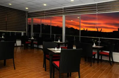 a restaurant with tables and chairs with a sunset in the window at Olive Hotel Amman in Amman