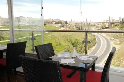 a dining room with a table and chairs and a large window at Olive Hotel Amman in Amman
