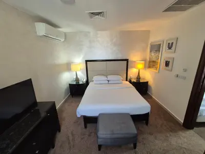 a bedroom with a bed and two lamps and a television at Le Vendome Hotel in Amman