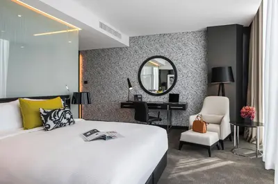 a bedroom with a bed and a desk and a mirror at Amman Rotana in Amman