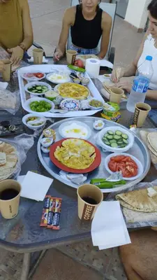 a group of people sitting around a table with food at Thara Real Estate in Sowayma