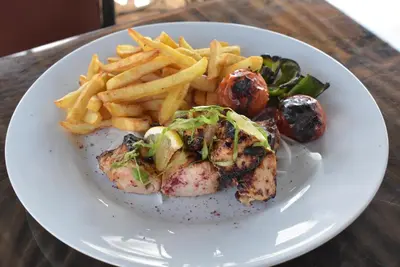 a white plate of food with french fries and meat at Bedouin Garden Village, hotel Dive in Aqaba
