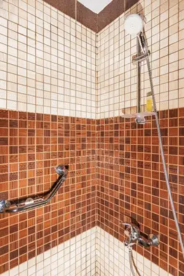 a shower in a bathroom with brown and white tiles at Sofia Hotel in Amman