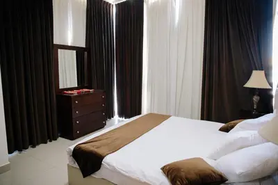 a bedroom with a large bed with a dresser and windows at Madina Suites in Amman