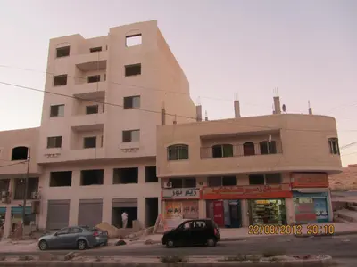 a large building with cars parked in front of it at Z apartment in Az Zarqa