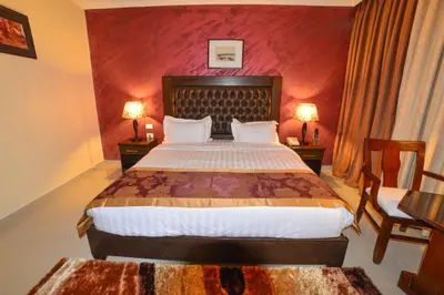 a bedroom with a large bed with two tables and two lamps at P Quattro Relax Hotel in Wadi Musa