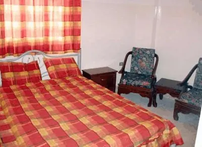 a bedroom with a bed and two chairs at Farah Hotel in Amman