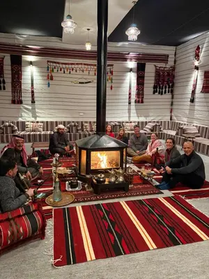 a group of people sitting around a table with a fireplace at Wadi Rum Bedouin Camp in Wadi Rum