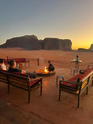 a group of people sitting around a fire in the desert at Wadi Rum Bedouin Camp in Wadi Rum
