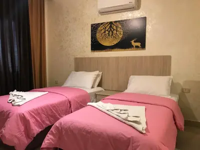 two beds in a room with pink sheets at Suzan Hotel Apartments in Amman