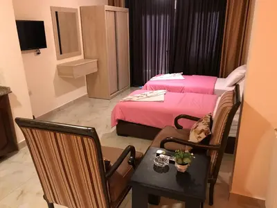 a small room with a bed and a table and chairs at Suzan Hotel Apartments in Amman
