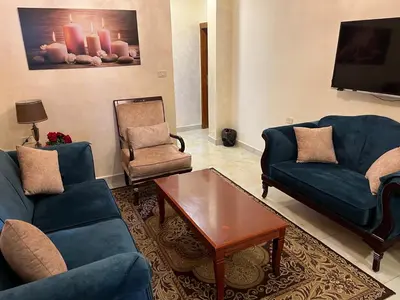 a living room with two blue couches and a coffee table at Suzan Hotel Apartments in Amman