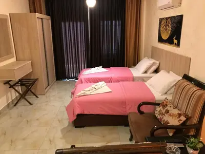 a hotel room with two beds and a chair at Suzan Hotel Apartments in Amman
