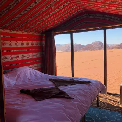 a bed in a room with a view of the desert at Khaled's Camp - Wadi Rum in Wadi Rum