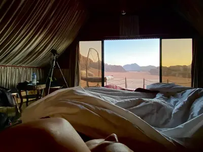 a person laying in a bed in a room with a window at Rum Stars Camp in Wadi Rum