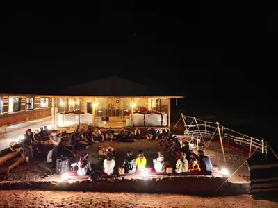 a group of people sitting outside of a building at night at Rum Stars Camp in Wadi Rum