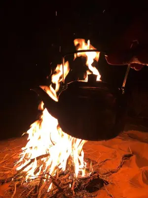 a person is stirring a pot over a fire at Milky Way Bedouin Camp in Wadi Rum