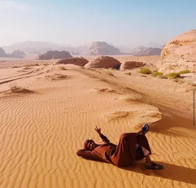 a man laying on the sand in the desert at Milky Way Bedouin Camp in Wadi Rum