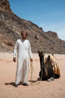 a man standing next to a camel in the desert at Milky Way Bedouin Camp in Wadi Rum