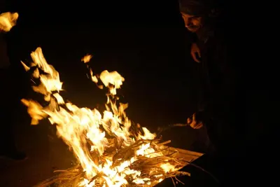 a man is standing next to a fire at Bedouin Traditions Camp in Wadi Rum