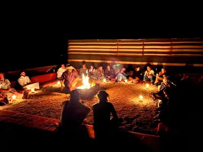 a group of people sitting around a fire pit at night at Bedouin Traditions Camp in Wadi Rum