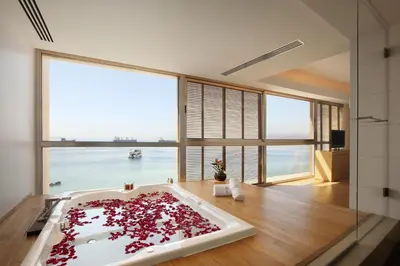 a bathroom with a bath tub filled with red petals at Kempinski Hotel Aqaba in Aqaba