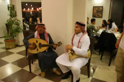 two men are sitting in chairs playing music at La Maison Hotel in Wadi Musa