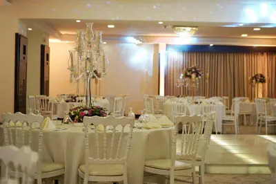 a room filled with tables and chairs with white table cloth at MENA Tyche Hotel Amman in Amman