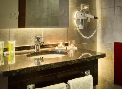 a bathroom with a sink with two glasses and a phone at Torino Hotel Amman in Amman
