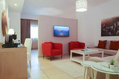 a living room with a couch and red chairs at Toledo Amman Hotel in Amman