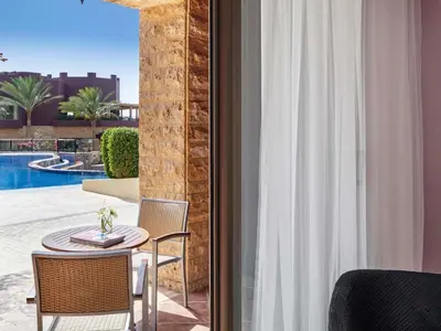 a patio with a table and chairs and a pool at Mövenpick Resort & Spa Tala Bay Aqaba in Aqaba