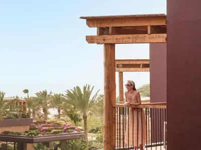 a woman standing on a balcony at a resort at Mövenpick Resort & Spa Tala Bay Aqaba in Aqaba