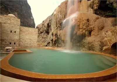 a pool of water in front of a waterfall at Ma'in Hot Springs in Sowayma