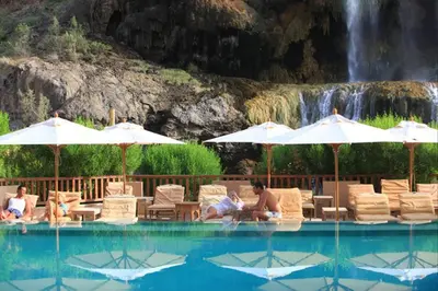 a group of people sitting in chairs next to a swimming pool at Ma'in Hot Springs in Sowayma