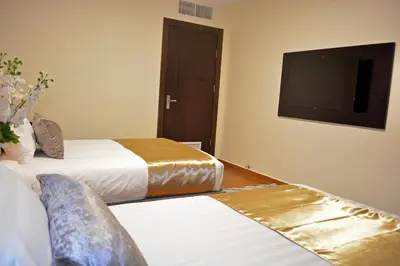 a hotel room with two beds and a flat screen tv at Tilal Almadina Hotel & Suites in Amman