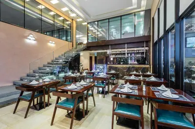 a restaurant with wooden tables and chairs and a staircase at Sulaf Luxury Hotel in Amman