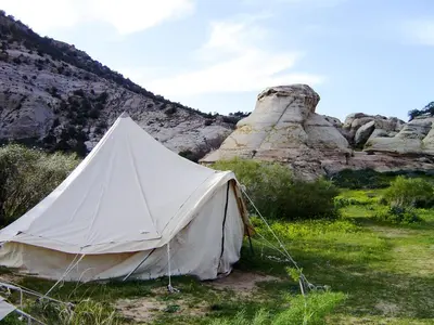 a white tent in a field near some rocks at Rummana Campsite in Dana