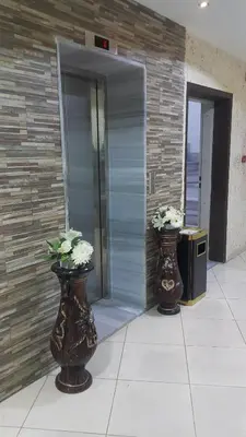two vases with flowers in them in front of an elevator at Al Fakher Hotel Apartments & Suites in Amman